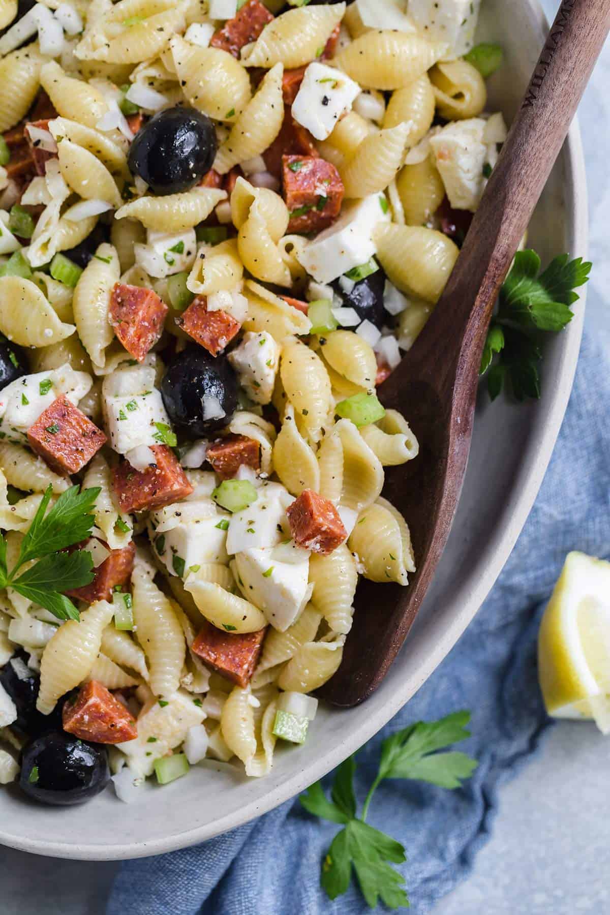 Close up photo of bowl of Italian pasta salad with wooden spoon.