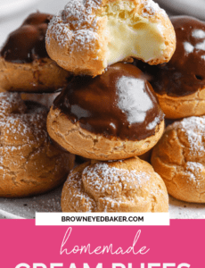 A stack of cream puffs that have been glazed with chocolate or dusted with powdered sugar on a plate with a pink box at the bottom that says Homemade Cream Puffs in white at the bottom.
