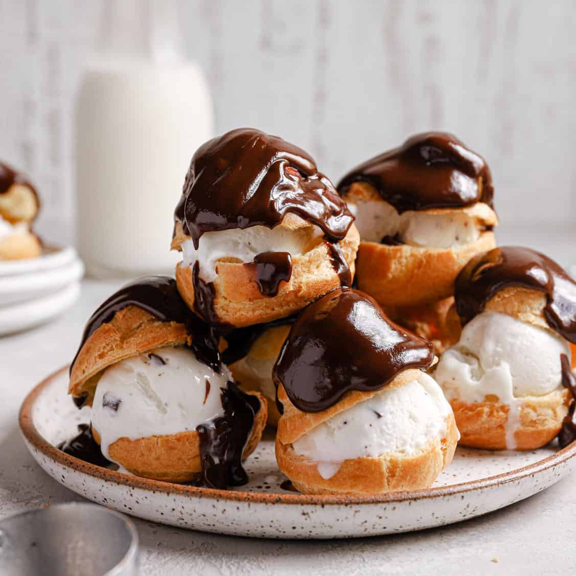 A stack of profiteroles with ice cream filling covered in chocolate sauce.