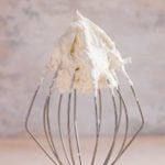 A square photo of vanilla buttercream frosting on a wire whisk.