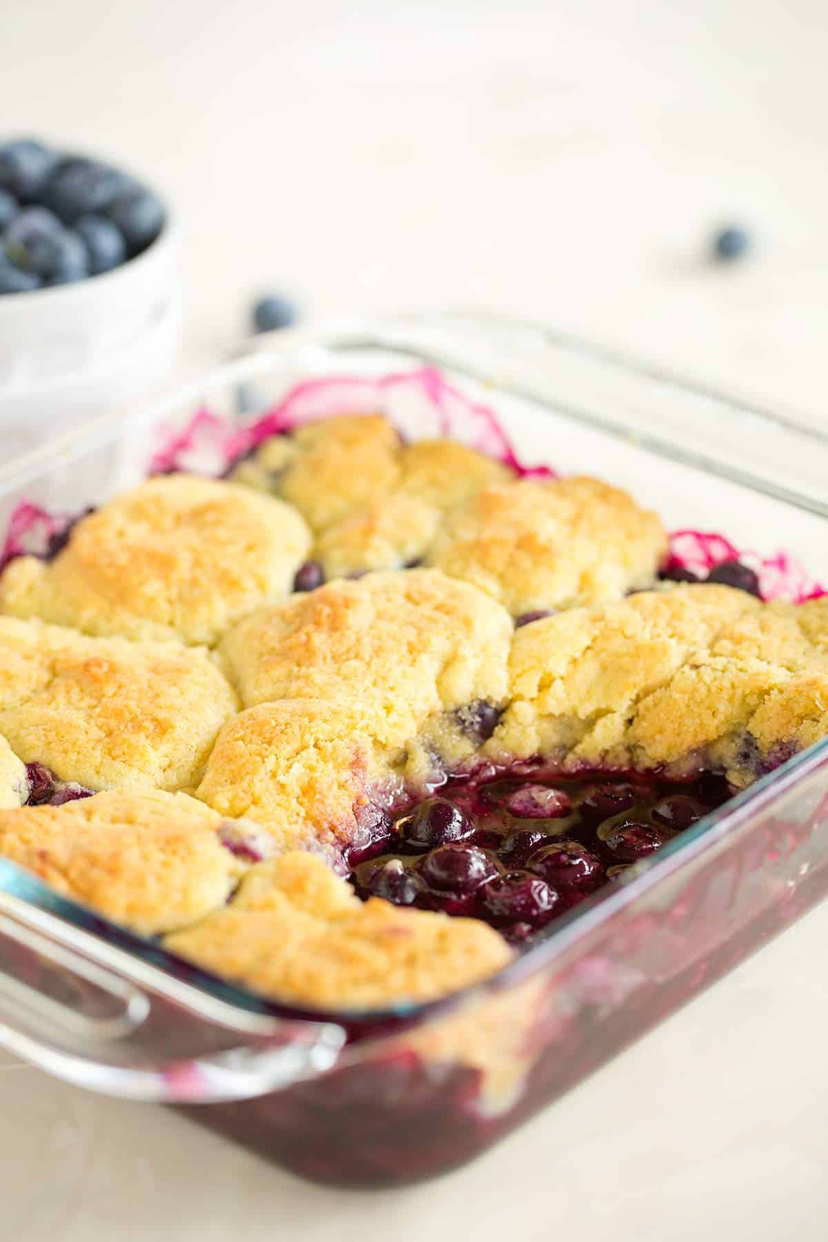 A pan of blueberry cobbler with a big scoop taken out.