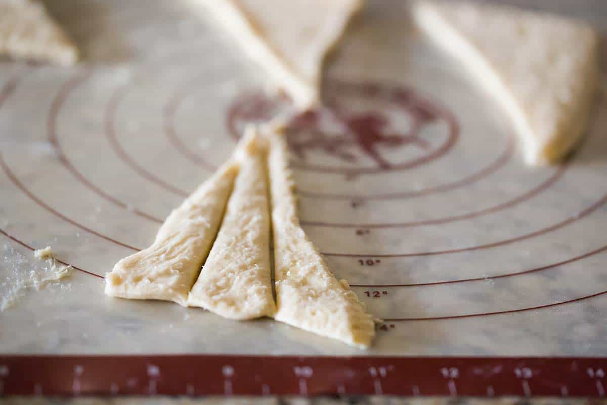 Crescent roll dough triangles sliced into three strips.