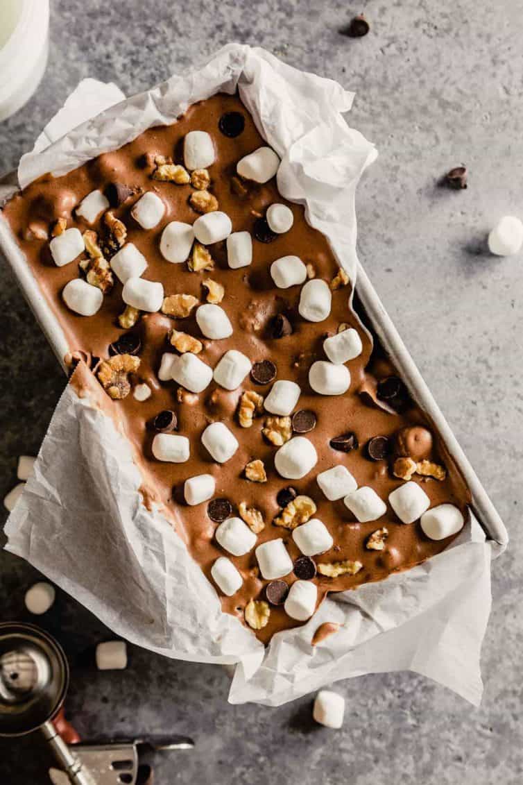 A top down photo of rocky road ince cream in a parchment paper lined bread loaf pan.