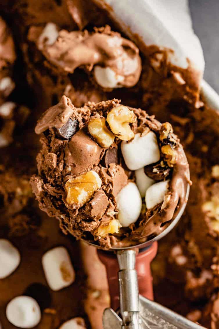 An ice cream scoop with a heaping scoop of rocky road ice cream.