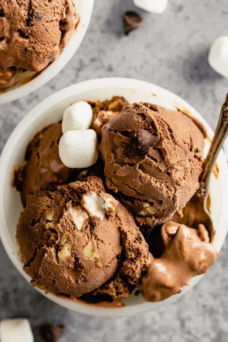 A white bowl filled with rocky road ice cream with a spoon in the right corner.