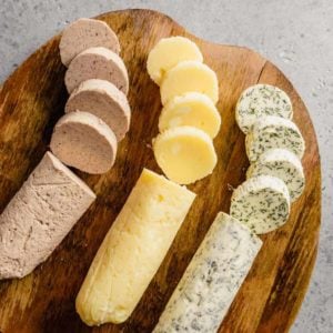 Three different compound butters cut in slices on a wooden cutting board.