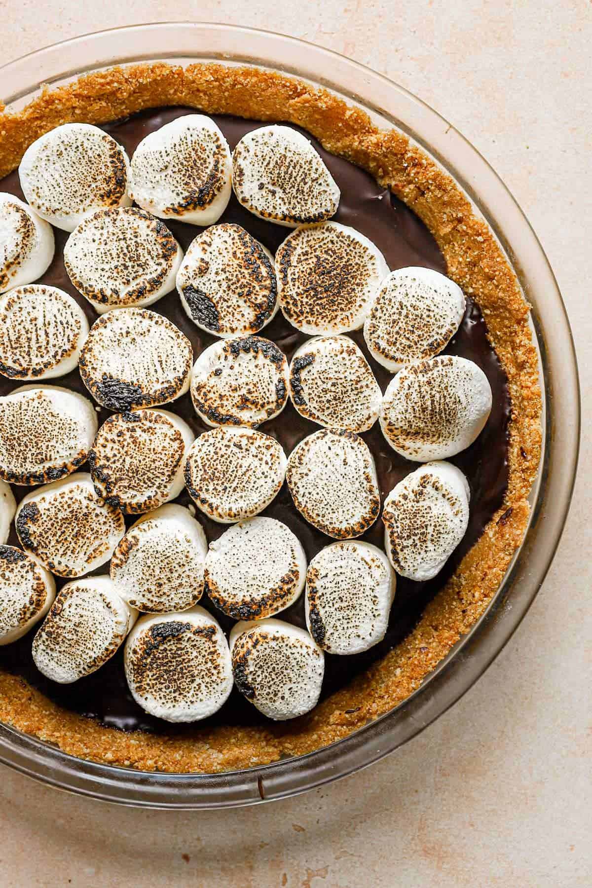 A no bake s'mores pie on a cooking rack on a peach counter.