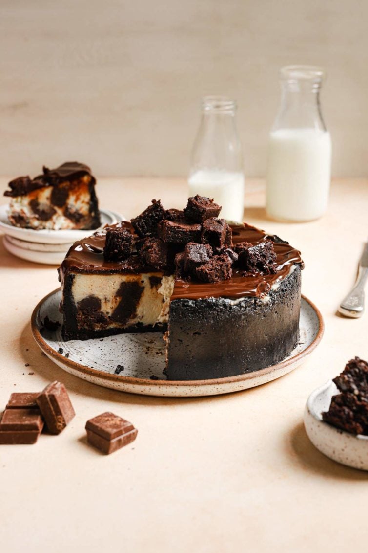 the whole brownie cheesecake with oreo crust and chocolate ganache with a slice removed