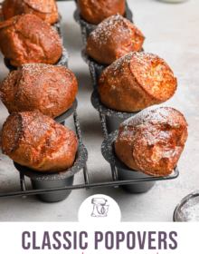 Golden brown baked breakfast popovers in a grey popover baking pan dusted with powdered sugar