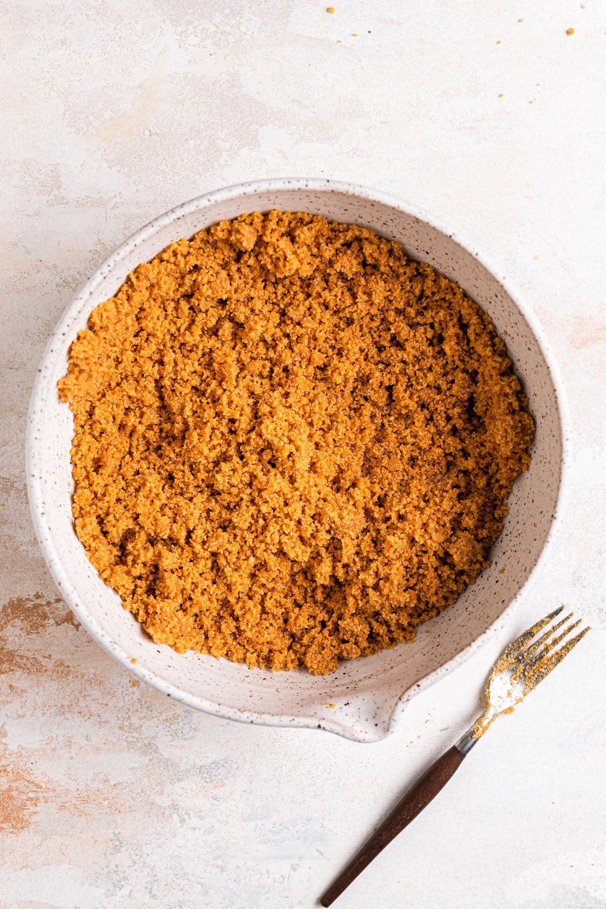 Graham cracker crust stirred together in a mixing bowl.