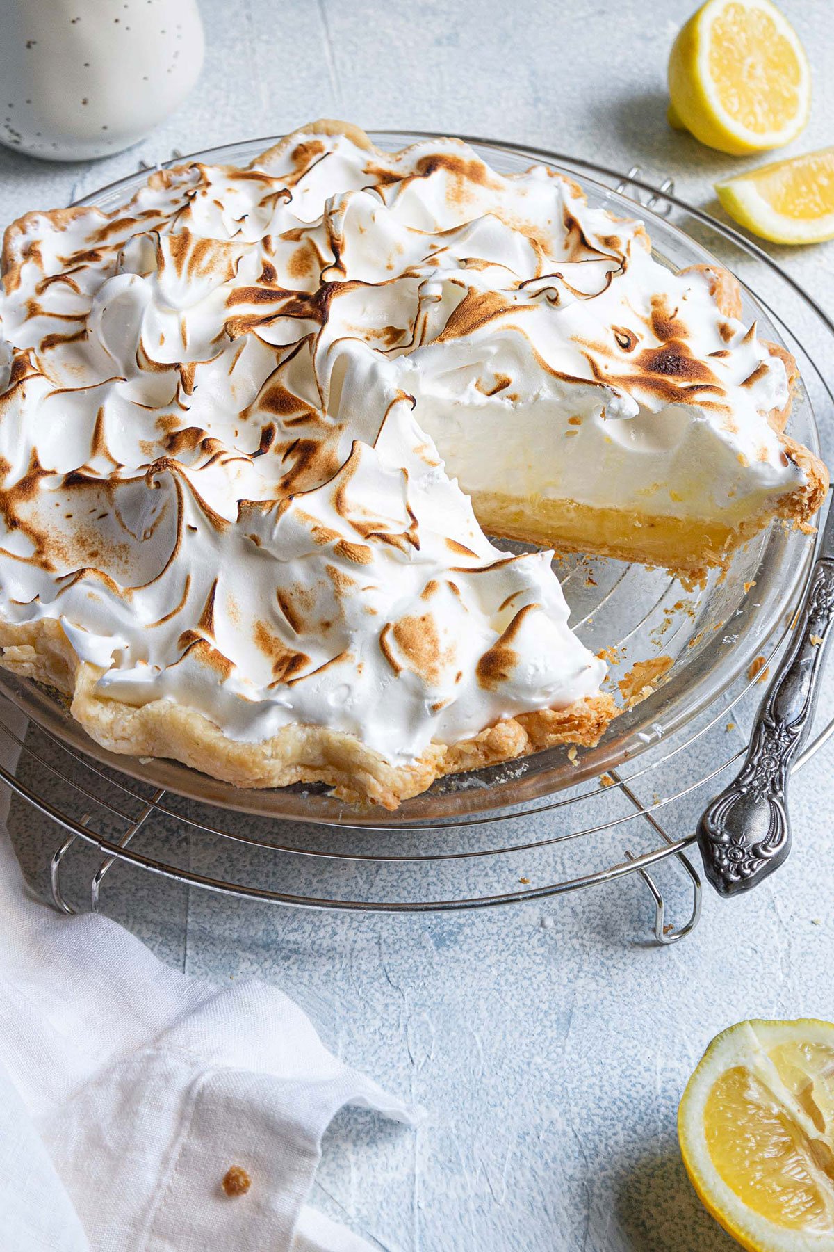 Lemon meringue pie in a glass pie plate with a slice removed.