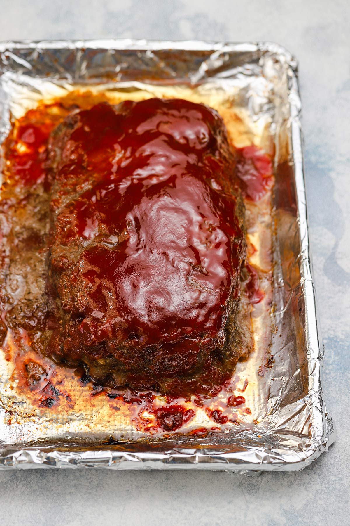 Overhead image of meatloaf after baking on an aluminum foil lined baking sheet.