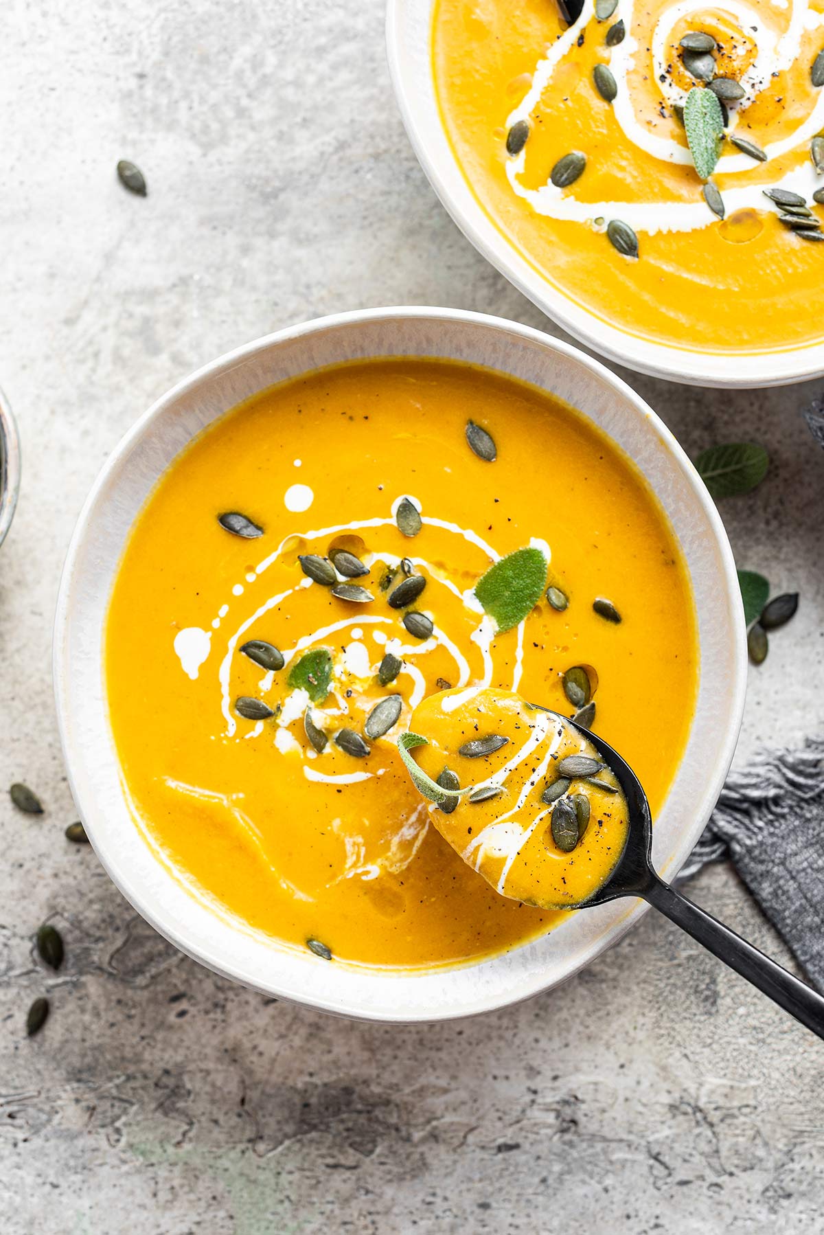 Overhead photo of pumpkin soup with spoon scooping out a spoonful.