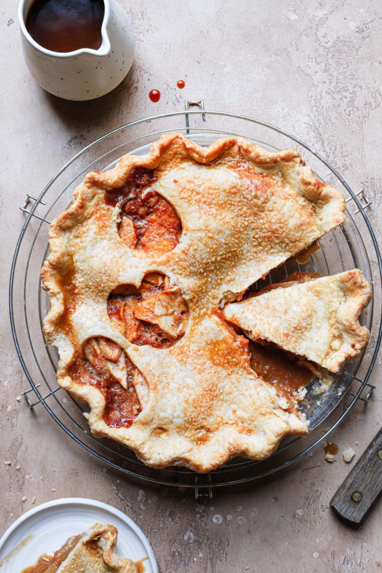 this salted caramel apple pie served in a glass pie dish with the salted caramel sauce