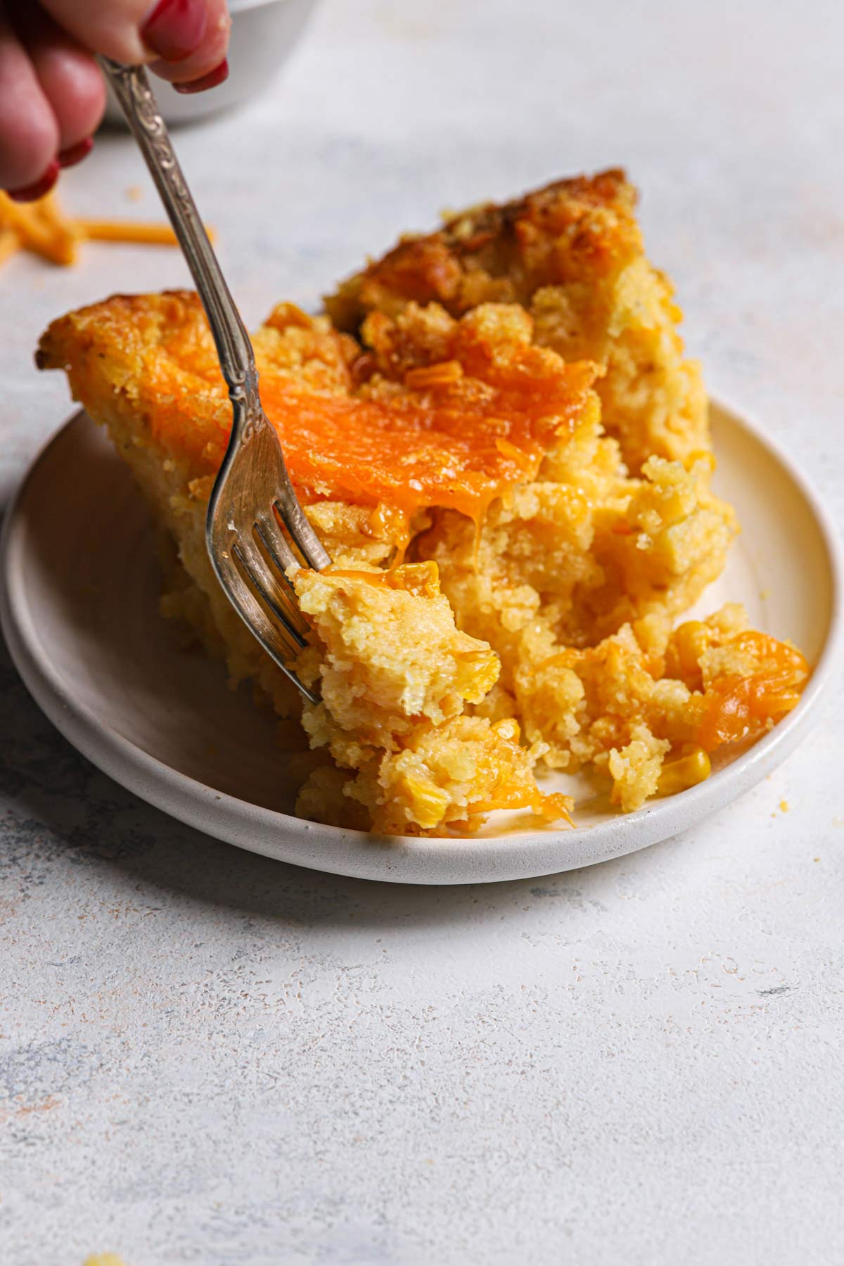 A serving of cheesy creamed corn casserole on a round plate.
