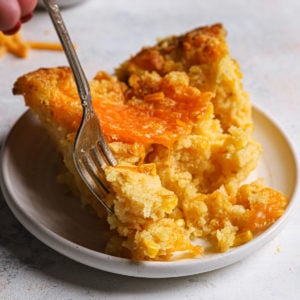A serving of cheesy creamed corn casserole on a round plate.