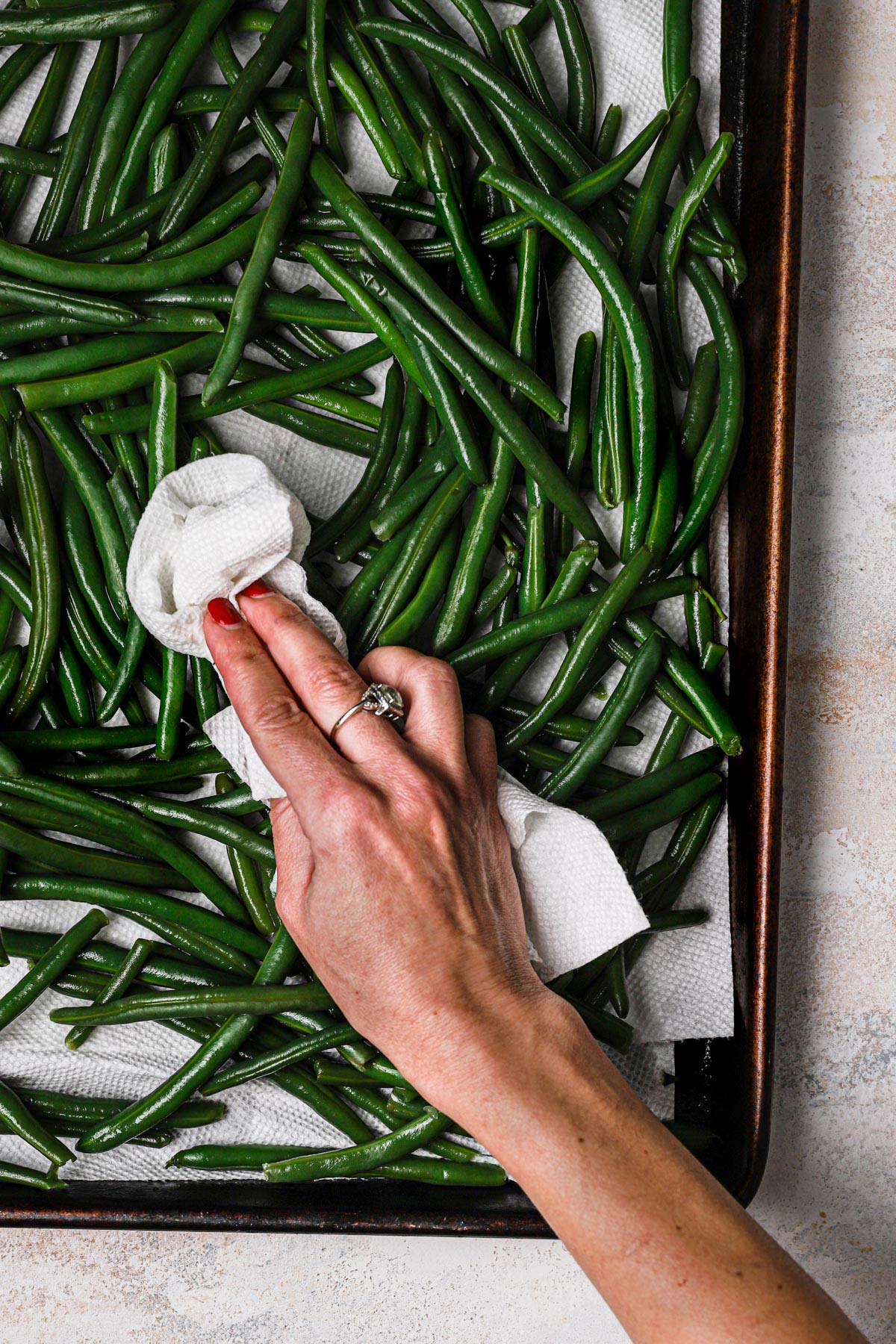 Green beans draining on paper towel-lined pan.