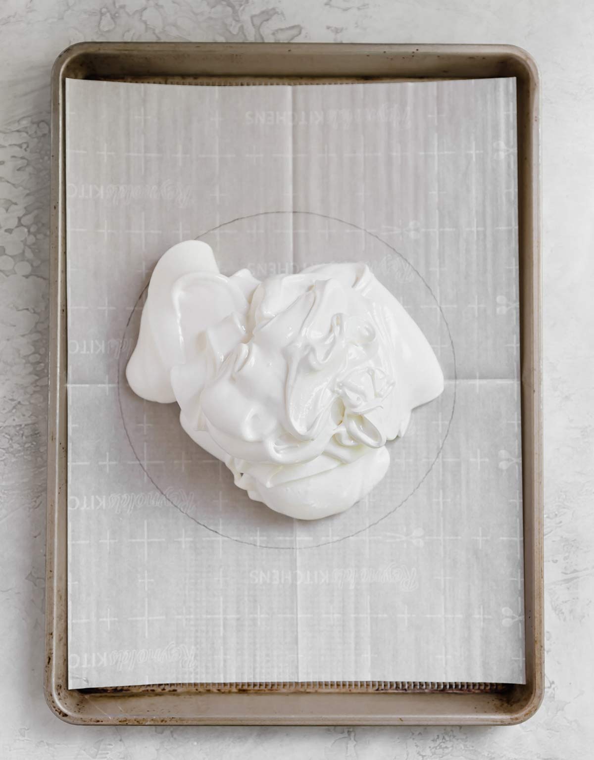 Meringue piled onto a parchment-lined baking sheet.