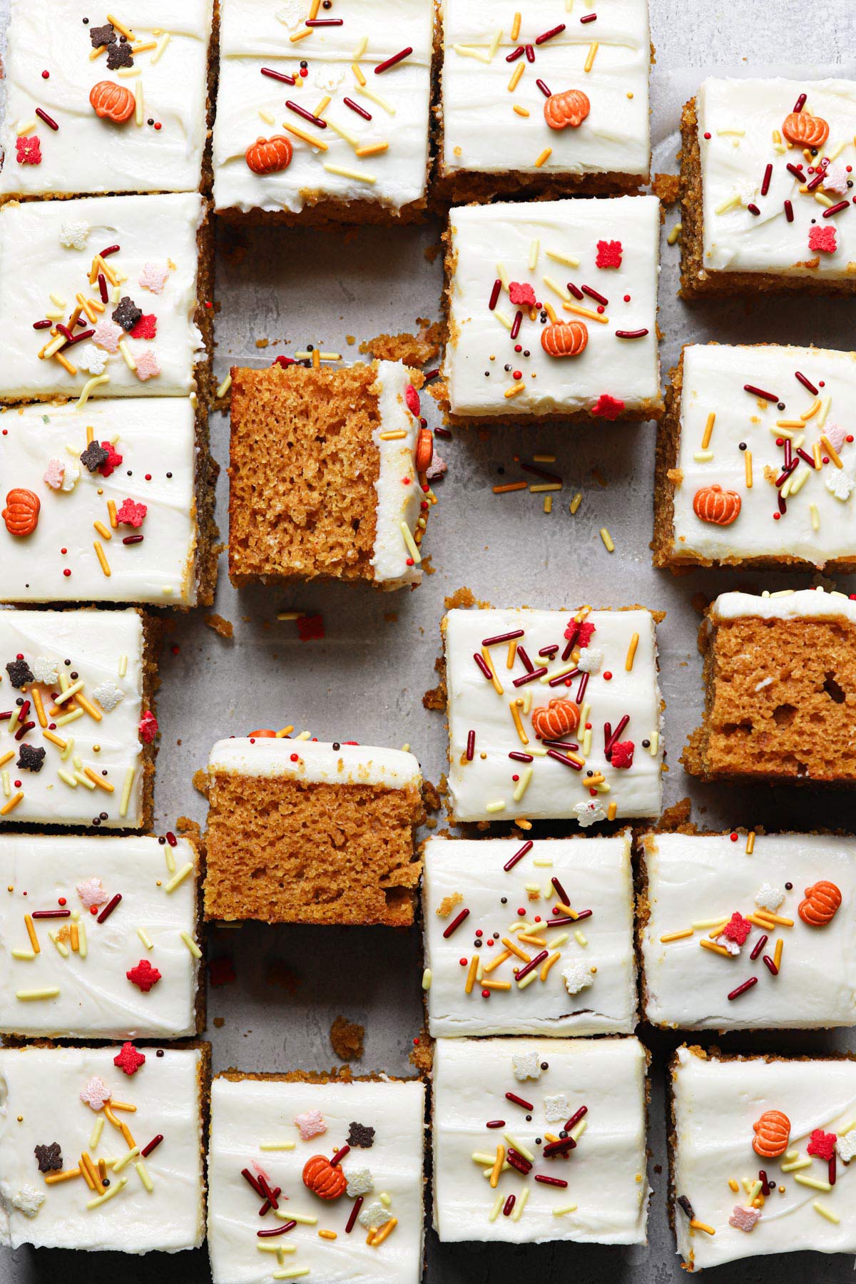 Pumpkin bars with cream cheese frosting cut into squares with some flipped sideways.
