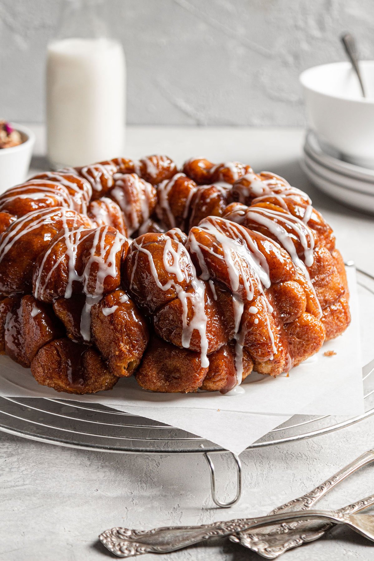 Baked monkey bread with vanilla icing on parchment paper.