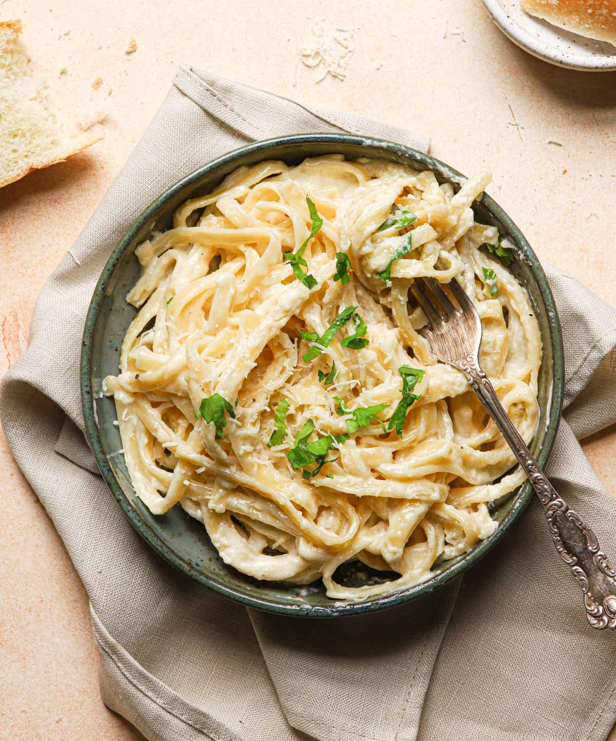 Bowl of fettuccine Alfredo sprinkled with parsley.
