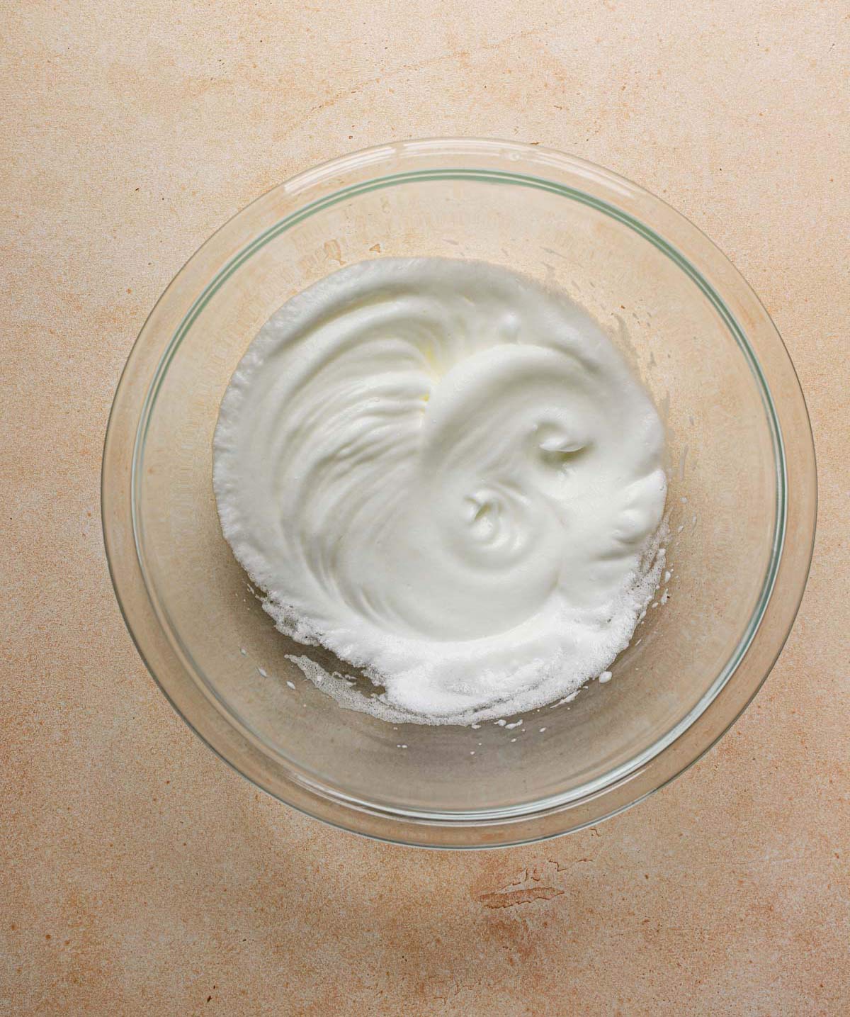 Whipped egg whites in a glass bowl.