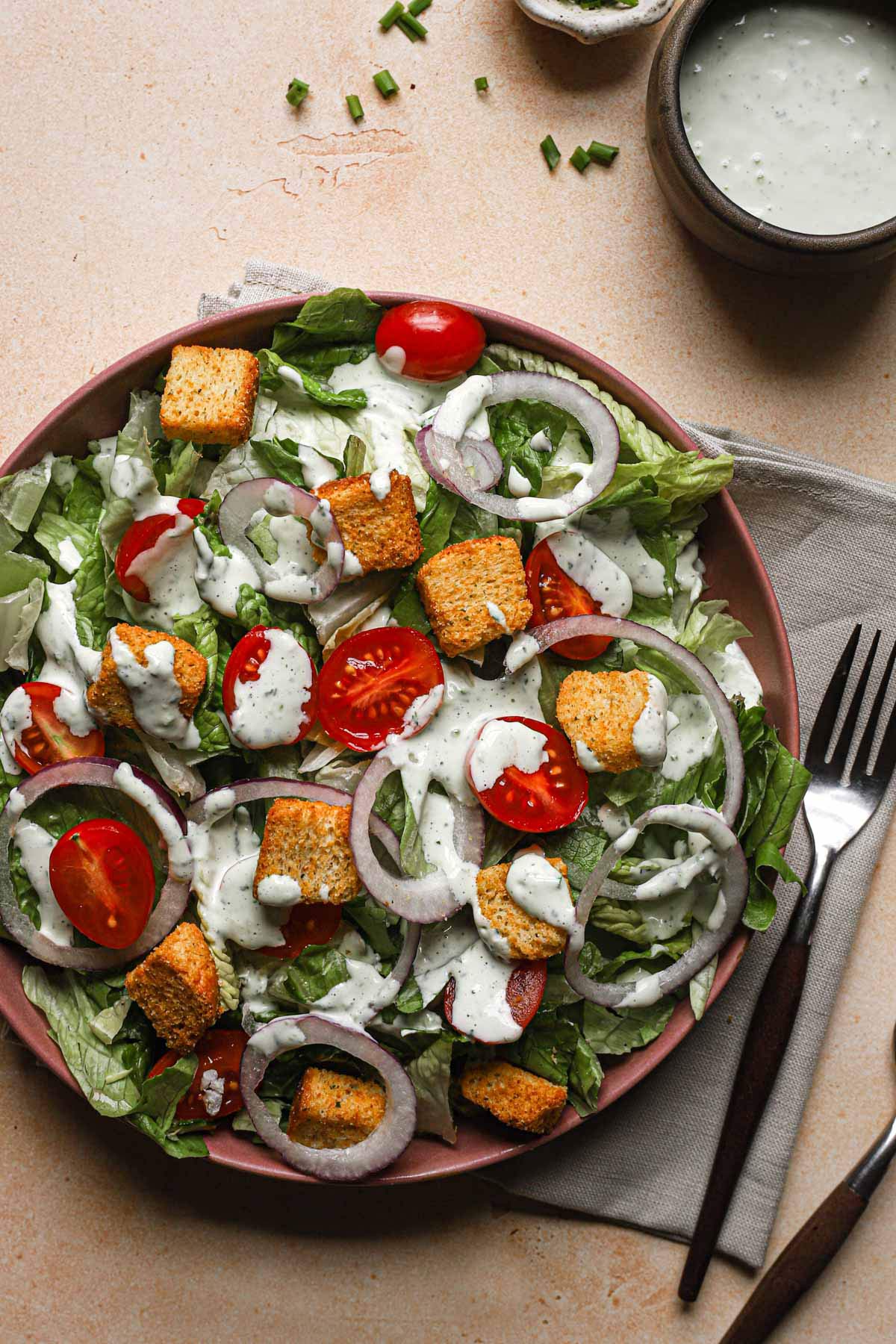 Salad with red onion, tomatoes, and croutons drizzled with homemade ranch dressing.