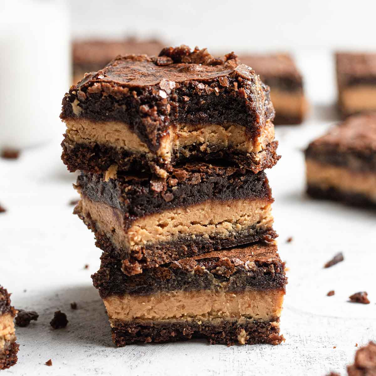 A stack of three peanut butter brownies with a bite taken out of the top brownie.