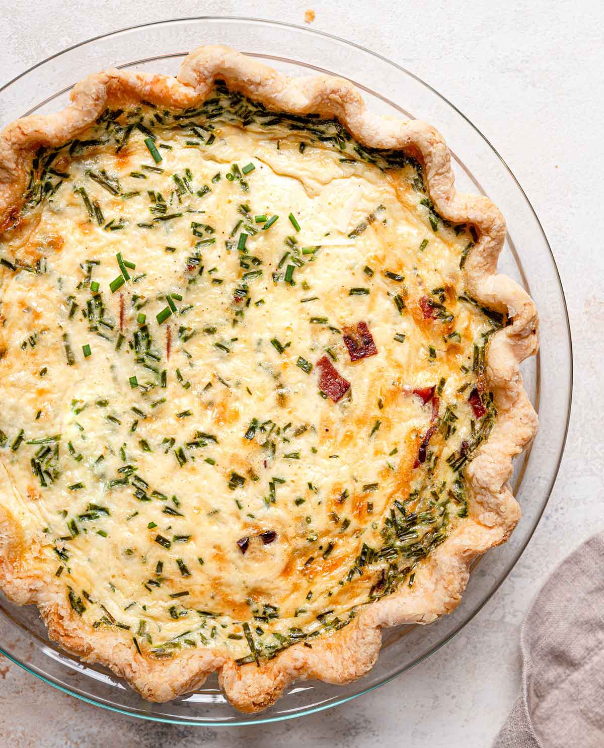 Overview photo of baked quiche Lorraine in glass pie plate.