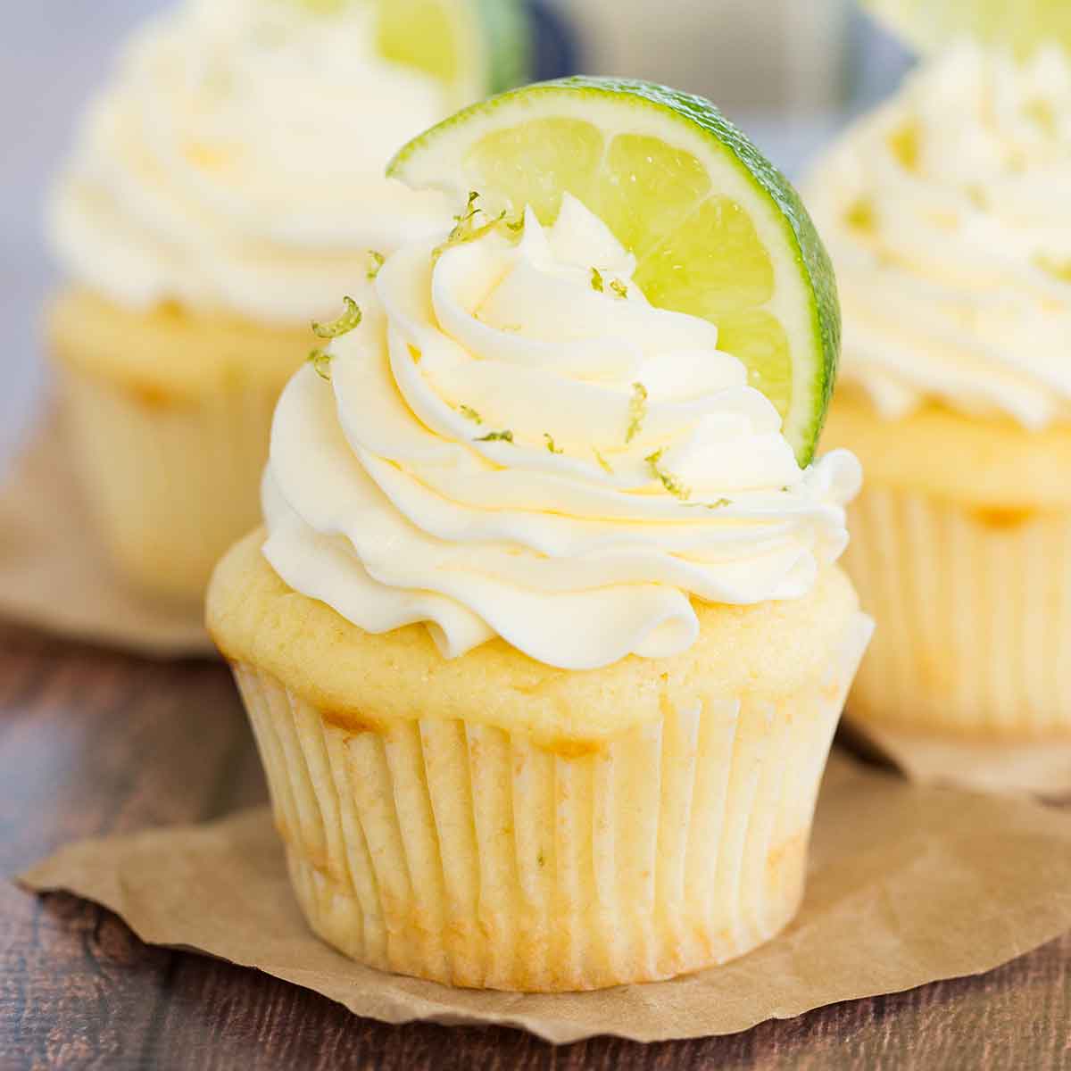 Margarita cupcake on brown parchment paper with a lime wedge and lime zest on top.