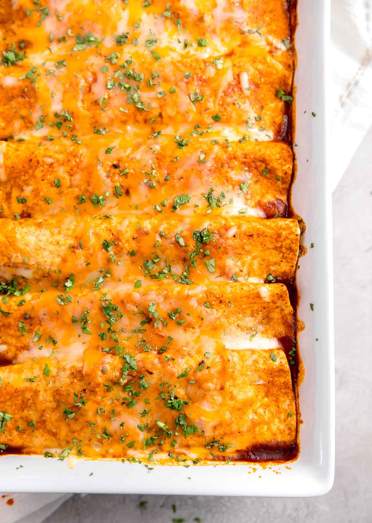 Overhead close up photo of baked enchiladas still in baking dish.