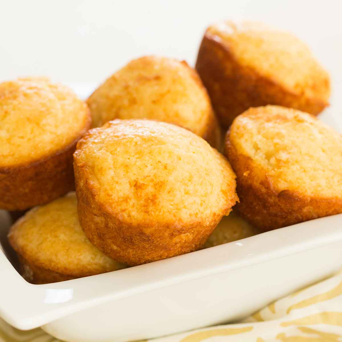A batch of honey muffins piled into a white bowl.