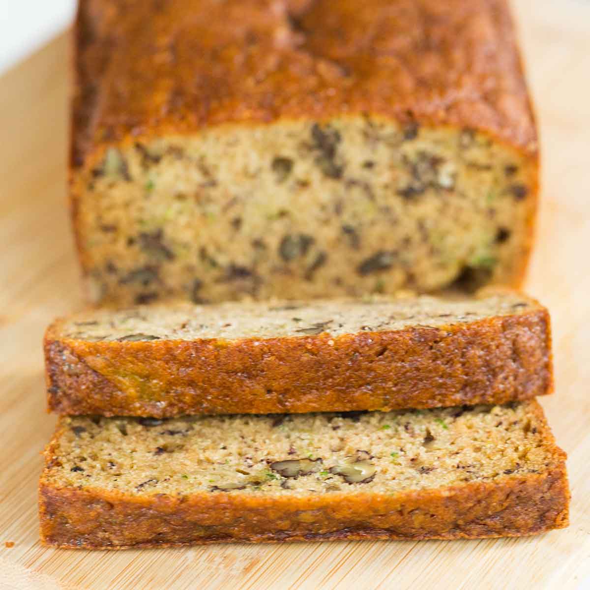 A loaf of zucchini banana bread with the first two slices cut off and laying on their side.