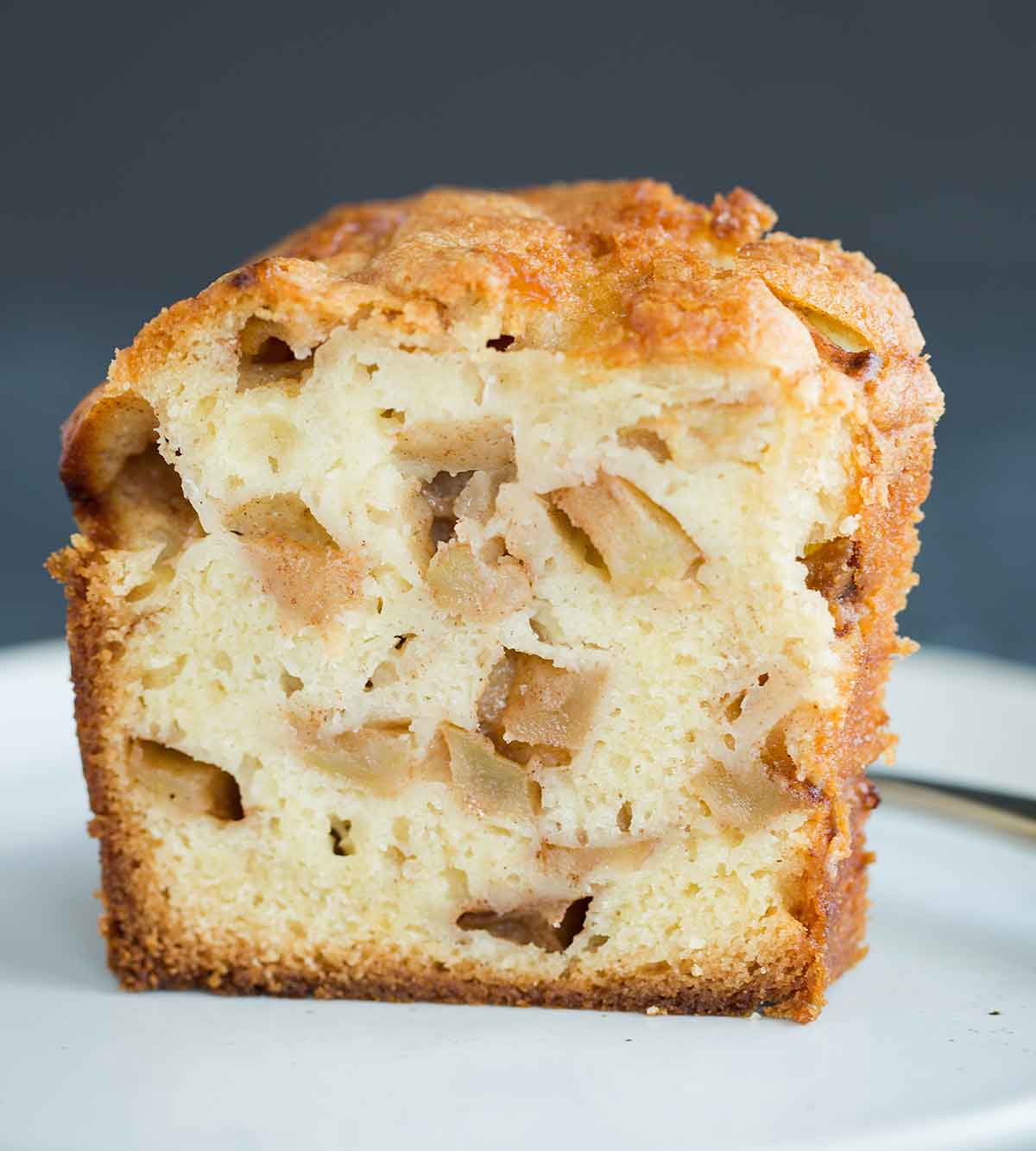 Slice of Jewish apple cake studded with chunks of cinnamon-sugar coated apples.