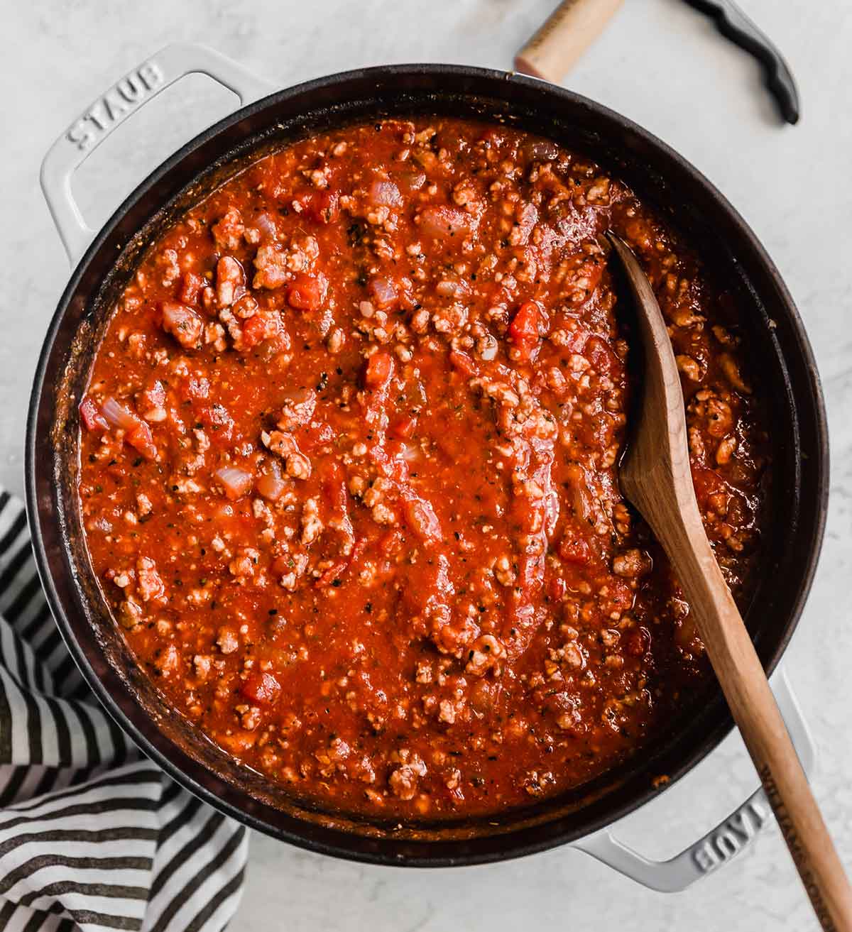Overhead photo of a pot of meat sauce with a wooden spoon in the pot.