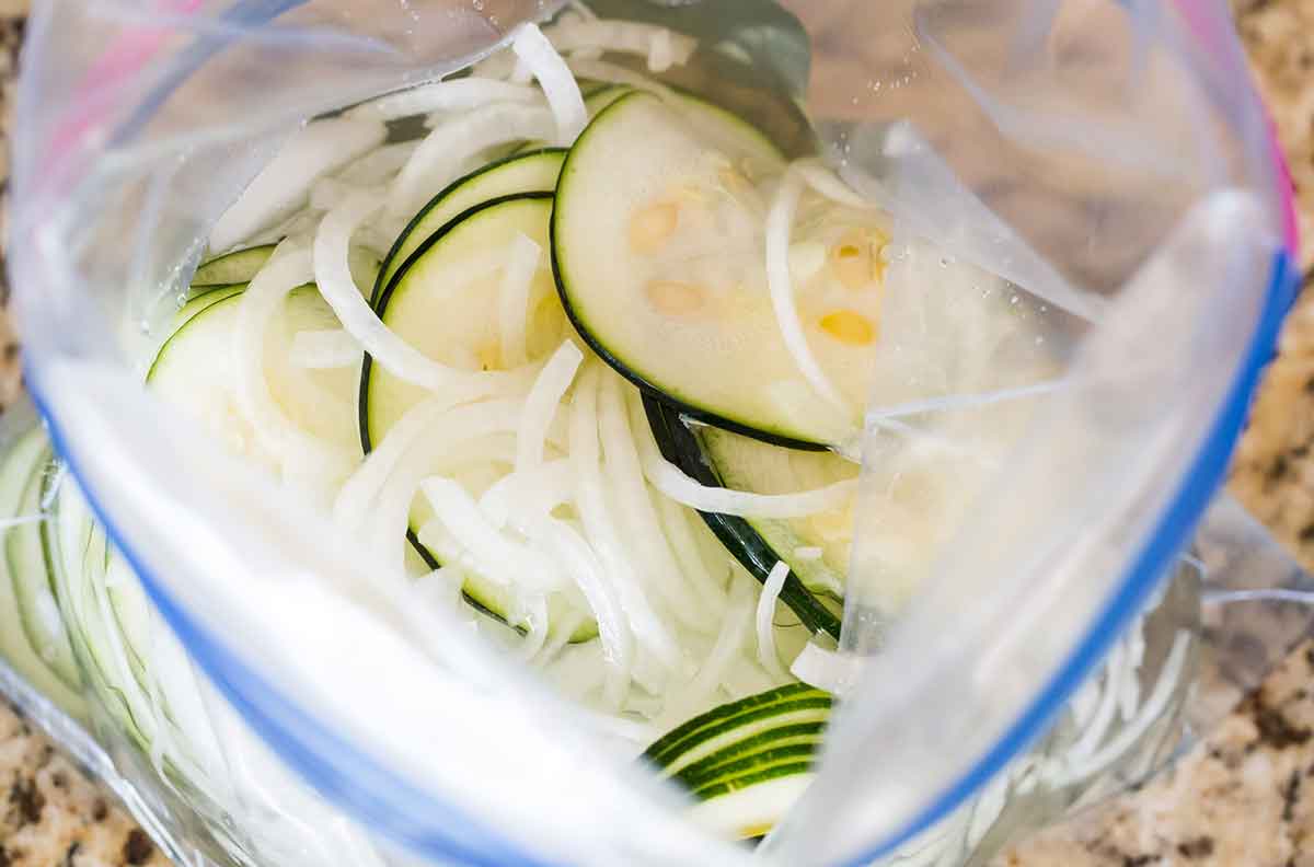 Sliced zucchini and onions in a large ziploc bag.