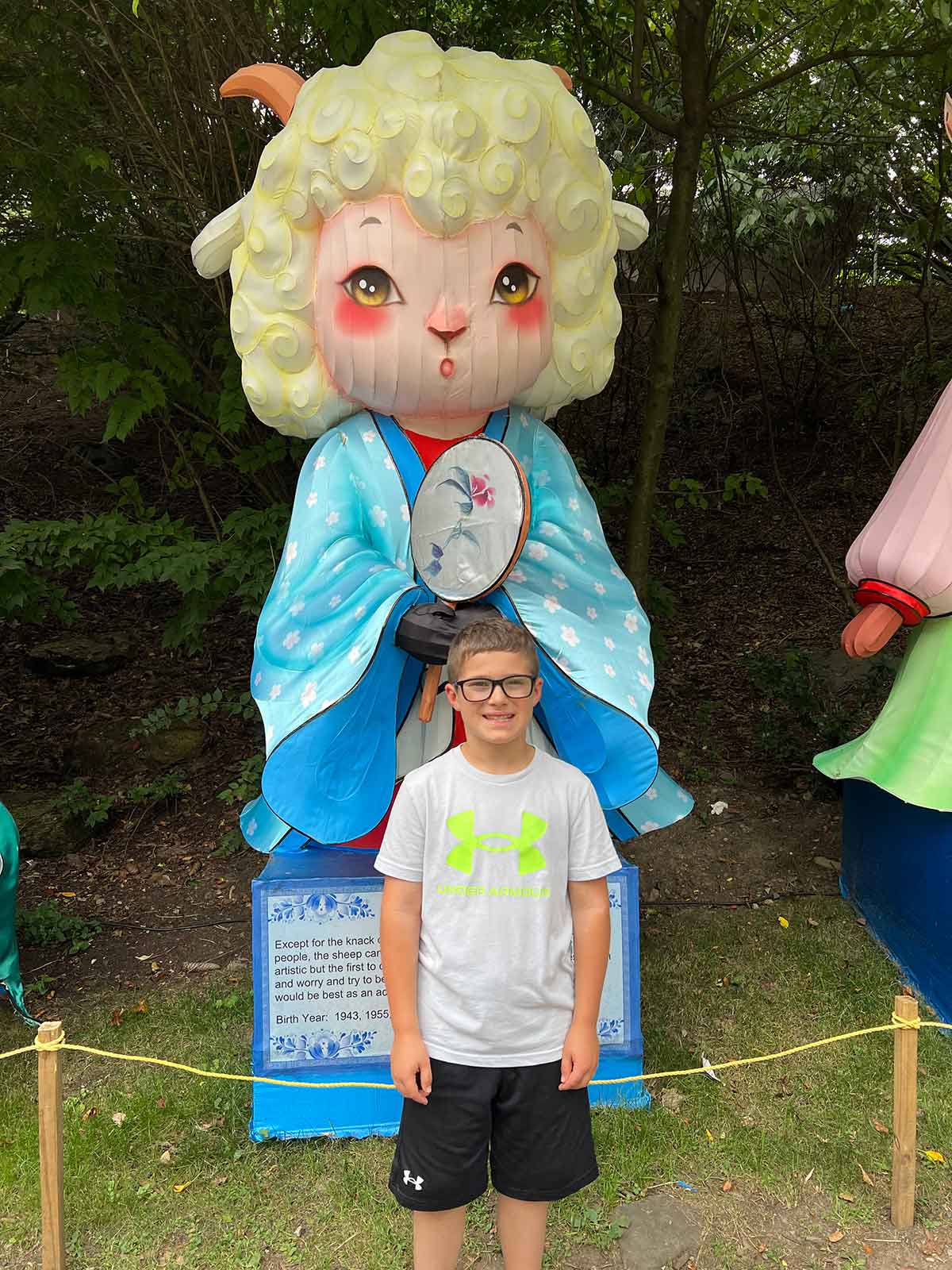 Boy standing in front of a large doll on display.