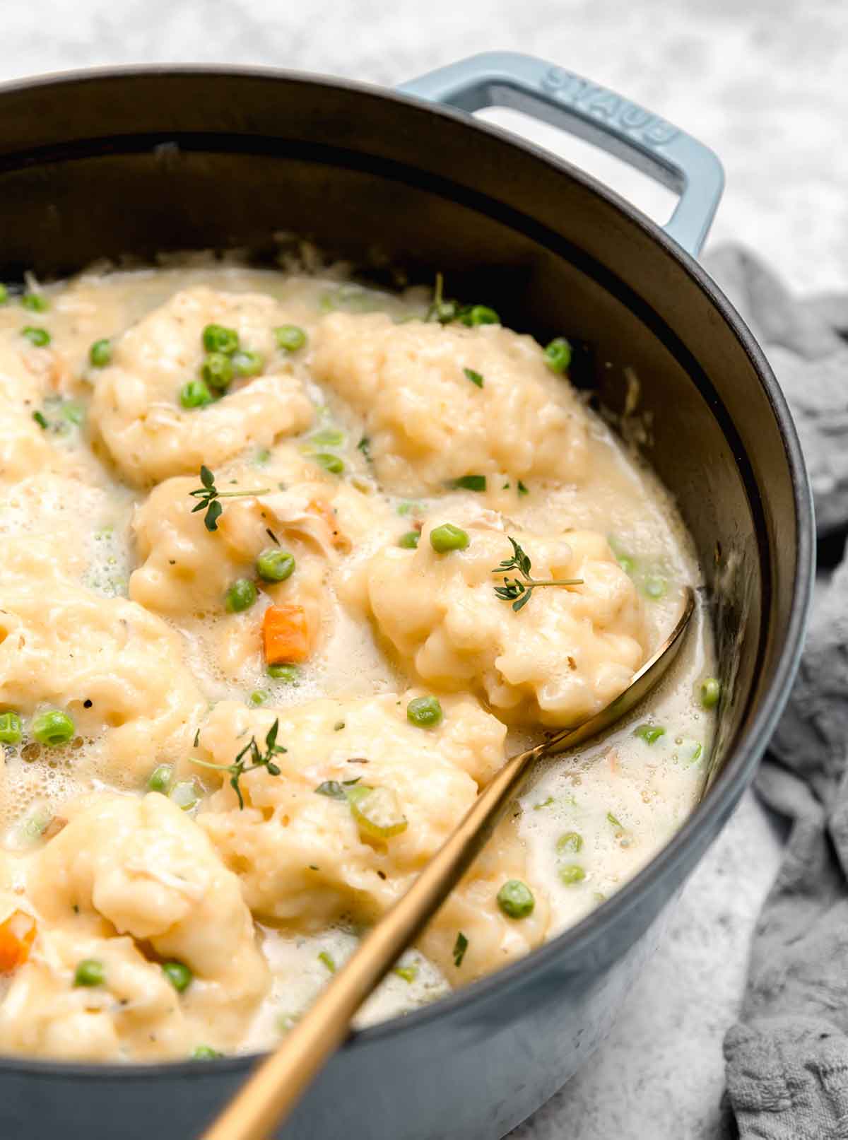Pot of chicken and dumplings with a metal spoon tucked underneath a dumpling.