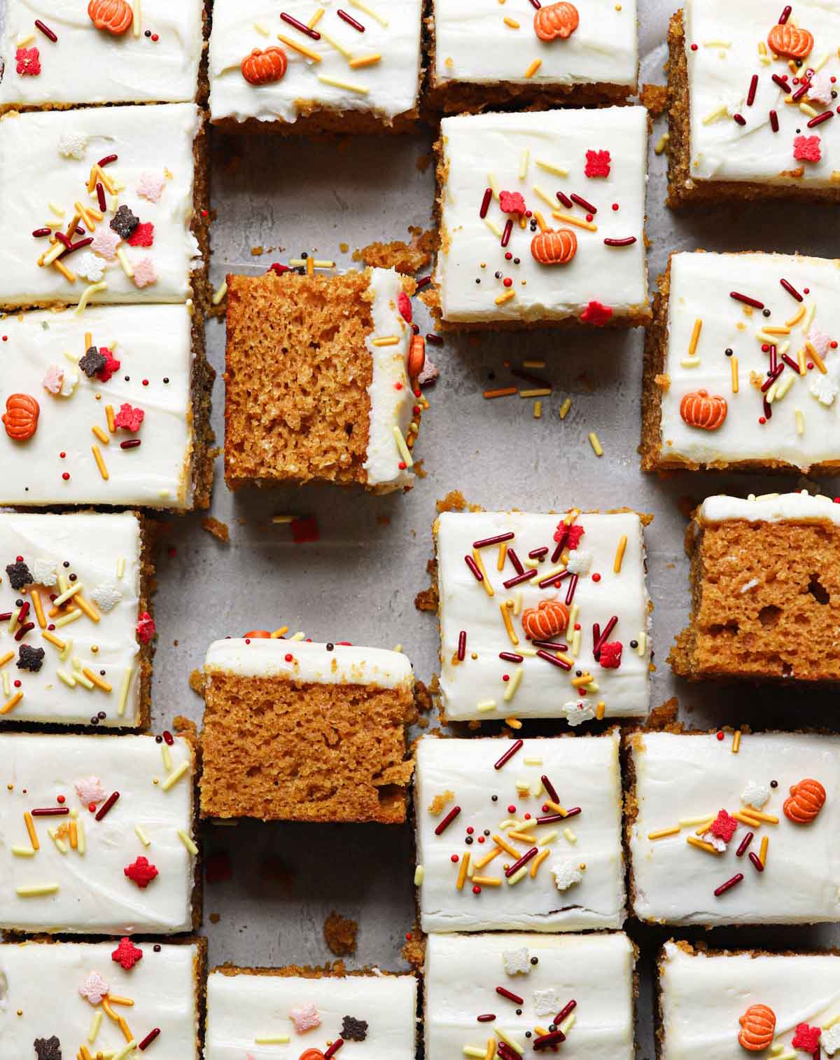 Overhead photo of pan of pumpkin bars cut into squares, with some turned on their sides so you can see the texture of the bar.