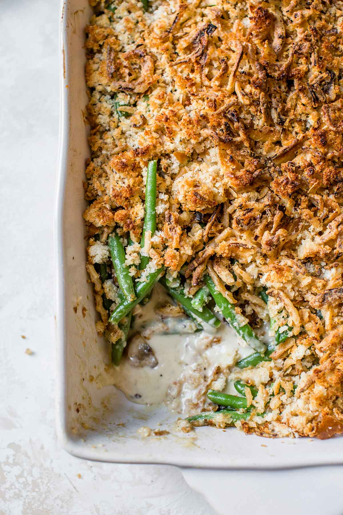 Overhead photo of green bean casserole with a scoop removed from the corner of the baking dish.