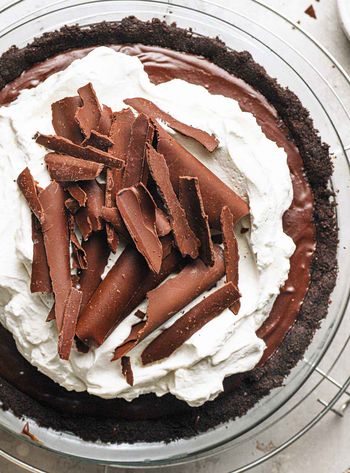 Overhead photo of chocolate cream pie in glass pie plate topped with whipped cream and chocolate curls.