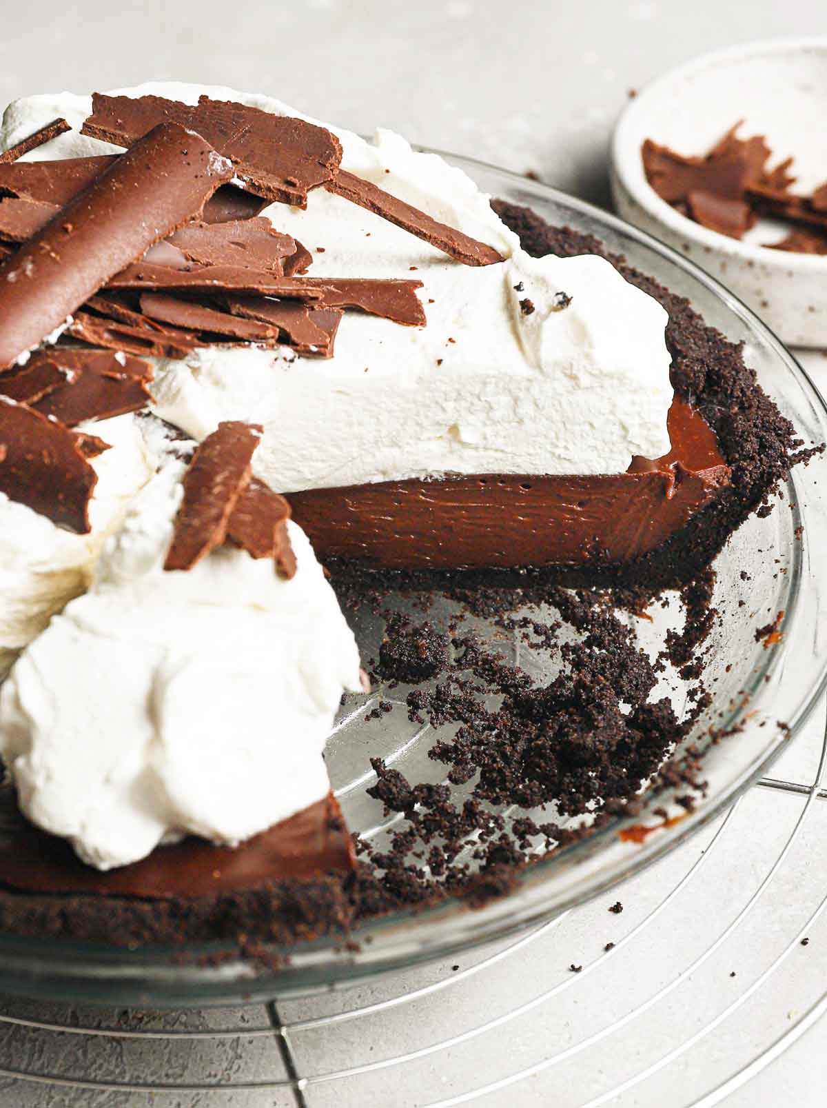 Chocolate cream pie in glass pie plate with a wedge of the pie missing.