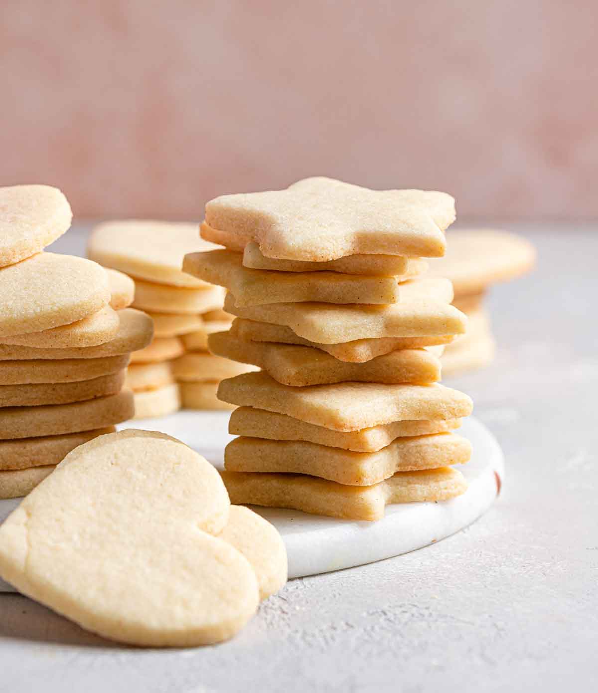 Heart and star-shaped cut out cookies plain and undecorated, in stacks on a white platter.