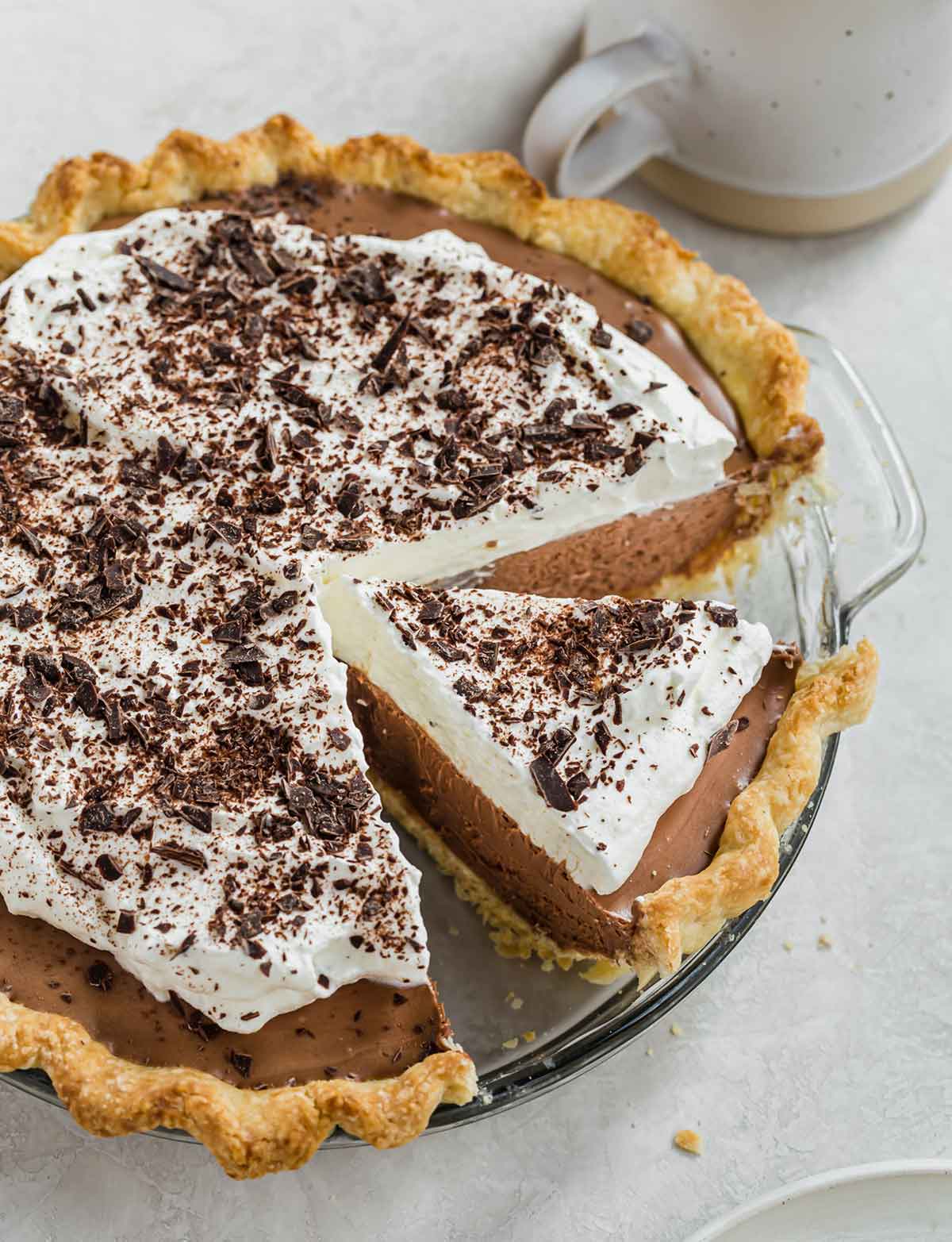 Overhead photo of French silk pie in glass pie plate with one slice cut away from rest of pie but still in the plate.