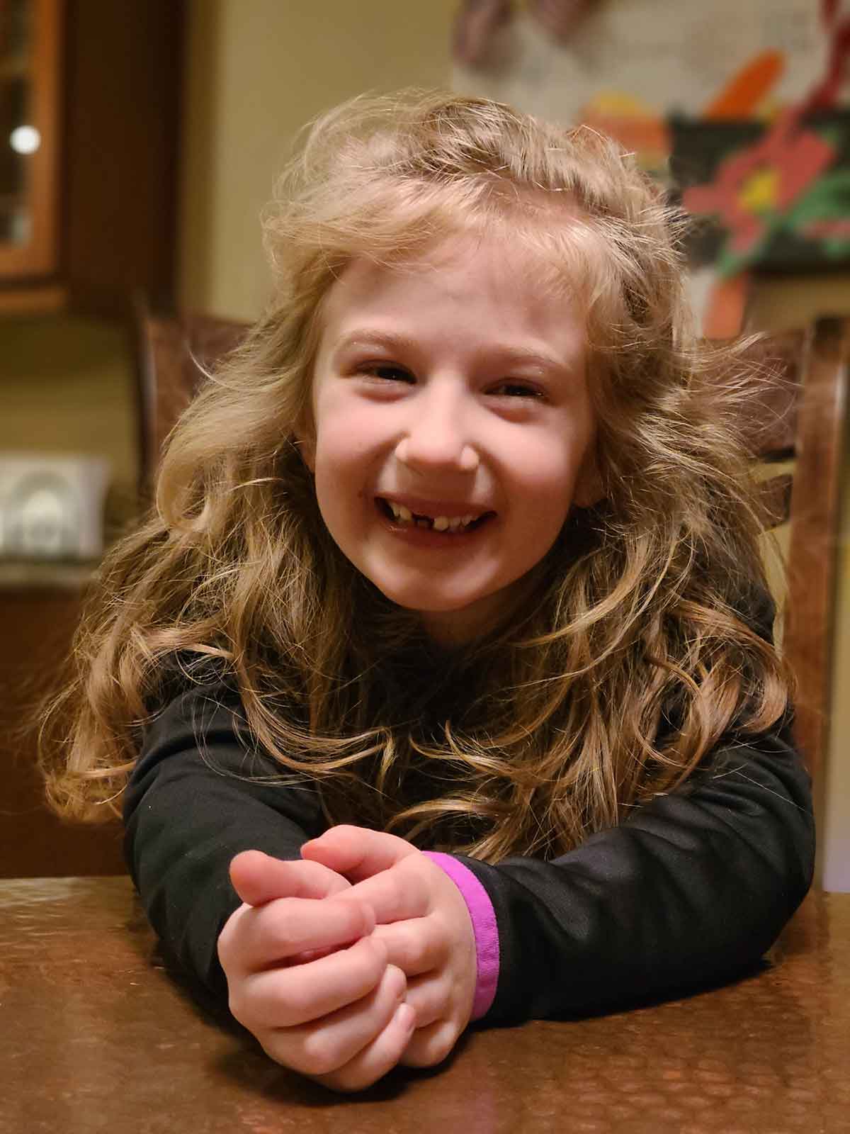 Little girl sitting at a table smiling.