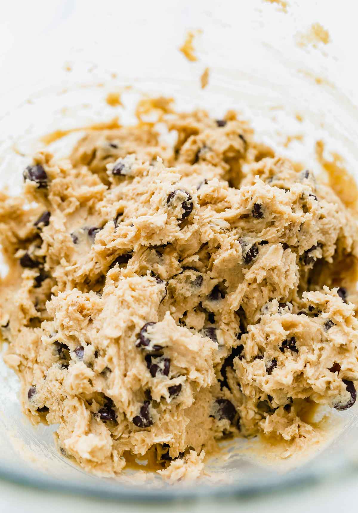 Peanut butter oatmeal chocolate chip cookie dough mixed together in a glass bowl.