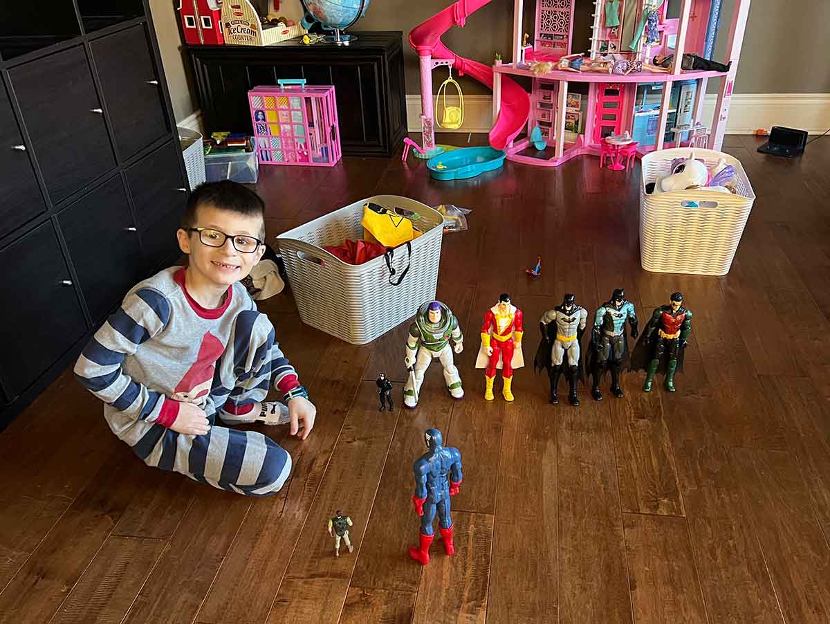 Little boy sitting on the floor playing with super hero action figures.