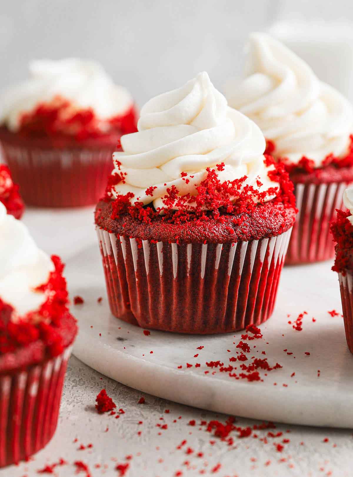 Close up photo of red velvet cupcake topped with cream cheese frosting and cake crumbles.