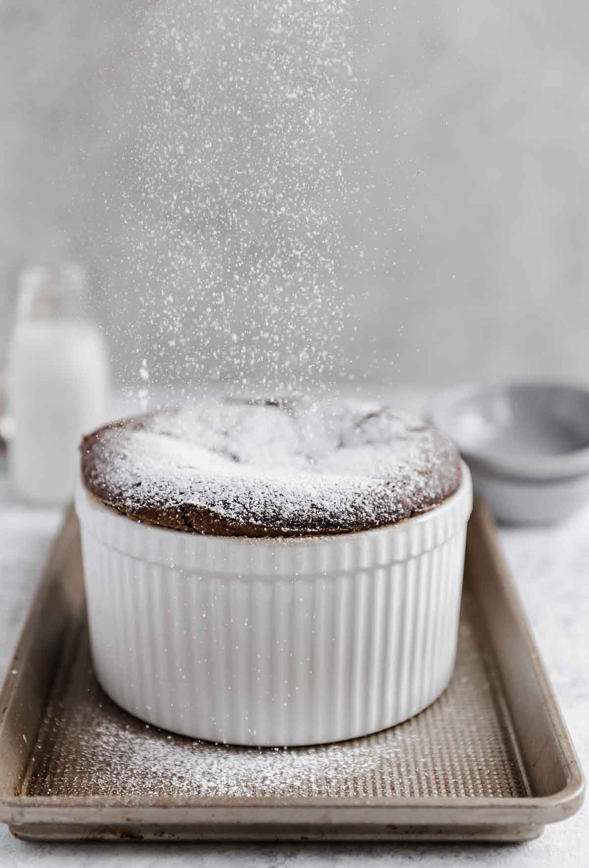 Photo of chocolate souffle being sprinkled with a large dusting of powdered sugar.
