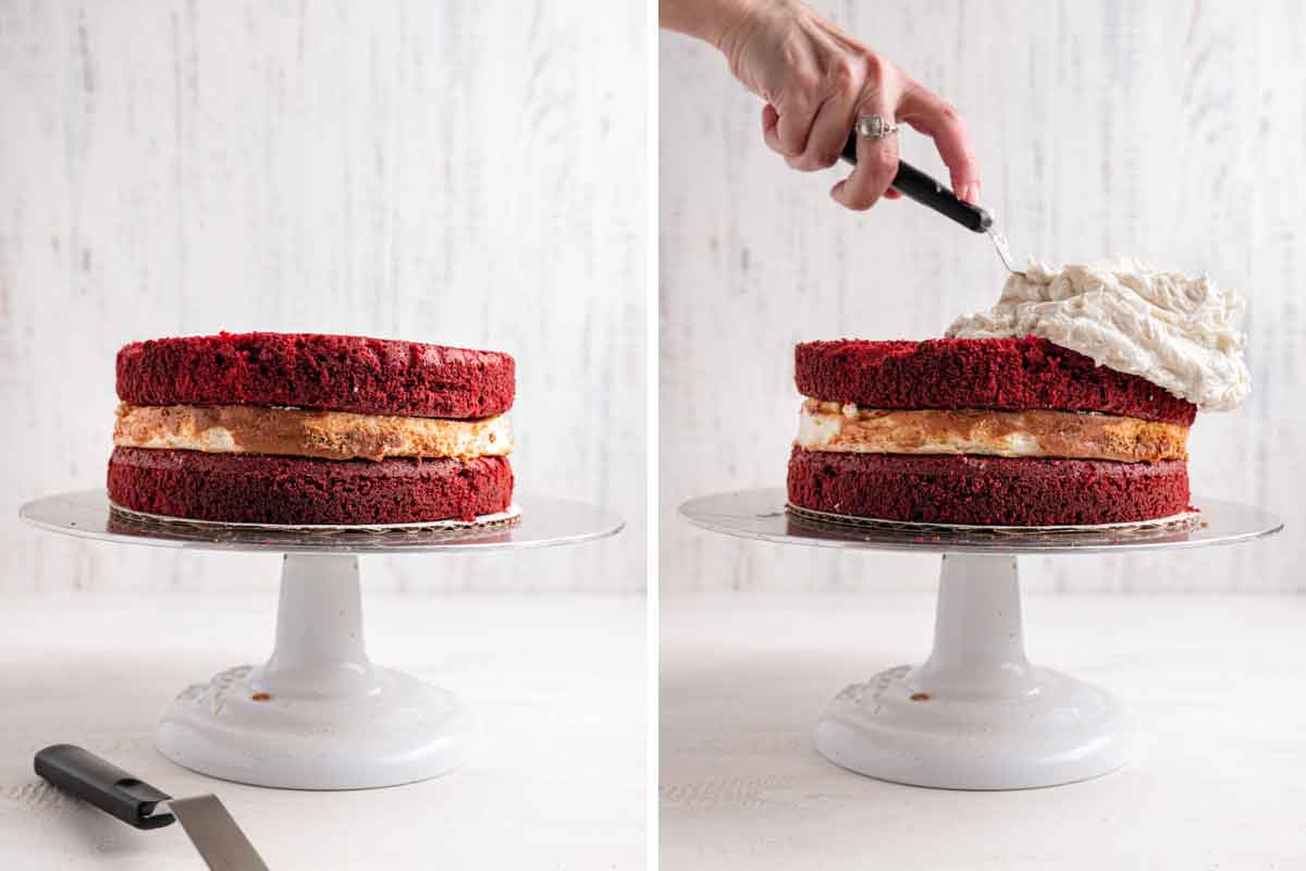 Red velvet cheesecake assembled on a cake stand, with cream cheese frosting being spread on top.